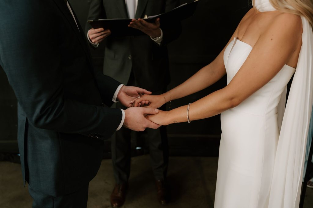 Lily and Ryan holding hands during their wedding ceremony