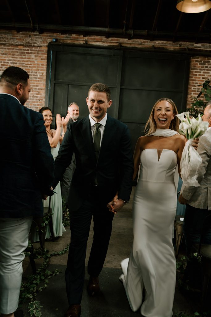 Lily and Ryan celebrating as they walk back up the aisle