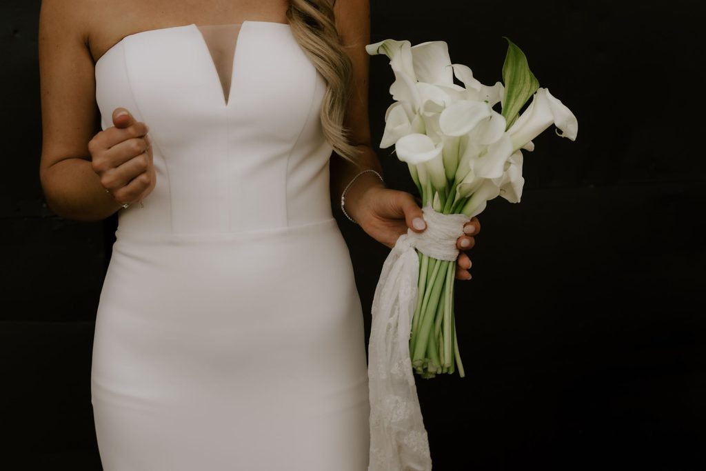 Close-up of Lily's bouquet and modern wedding dress