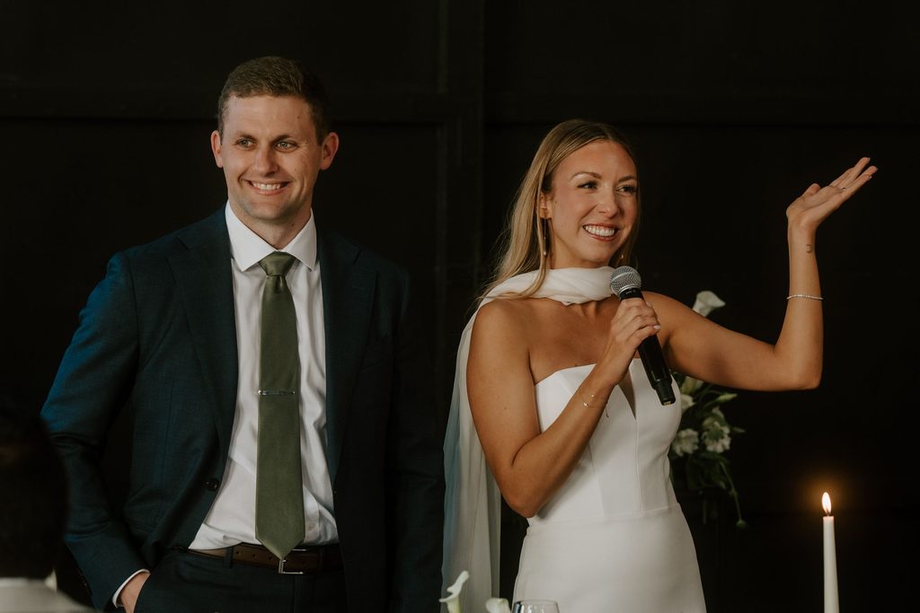 Lily and Ryan smiling during their wedding reception speeches