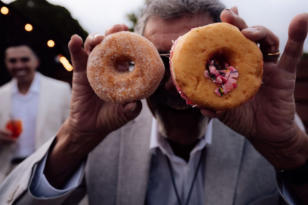 Wedding guest holding two doughnuts at The Penny reception