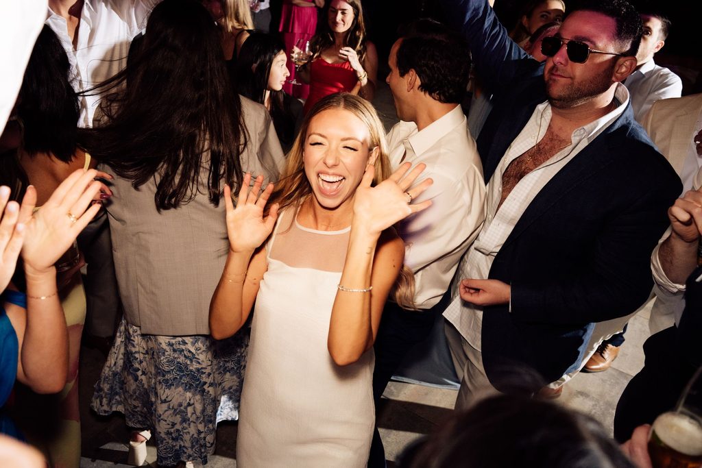 Lily laughing with guests on the crowded wedding dance floor