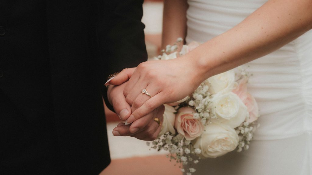Vanessa and Bryant holding hands beside her bouquet