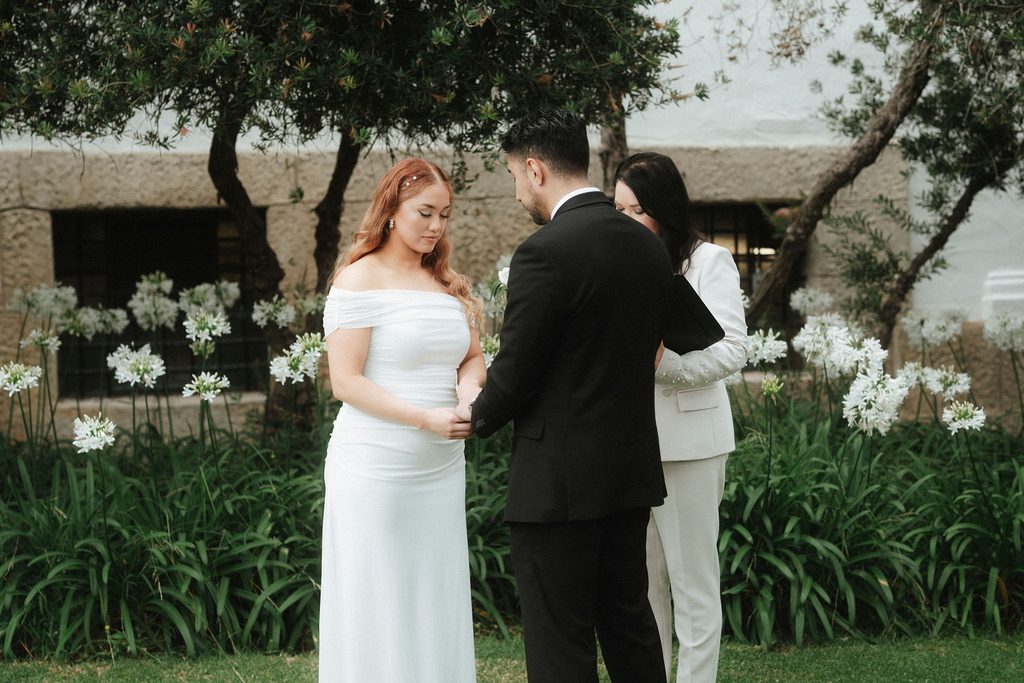 Vanessa and Bryant holding hands beneath a tree during their ceremony
