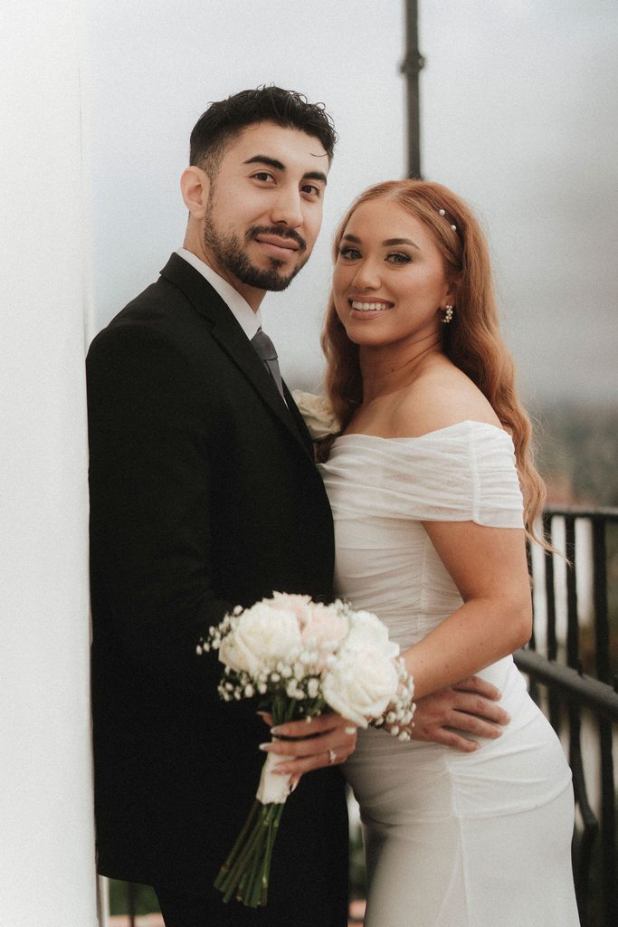 Vanessa and Bryant smiling together on a courthouse balcony