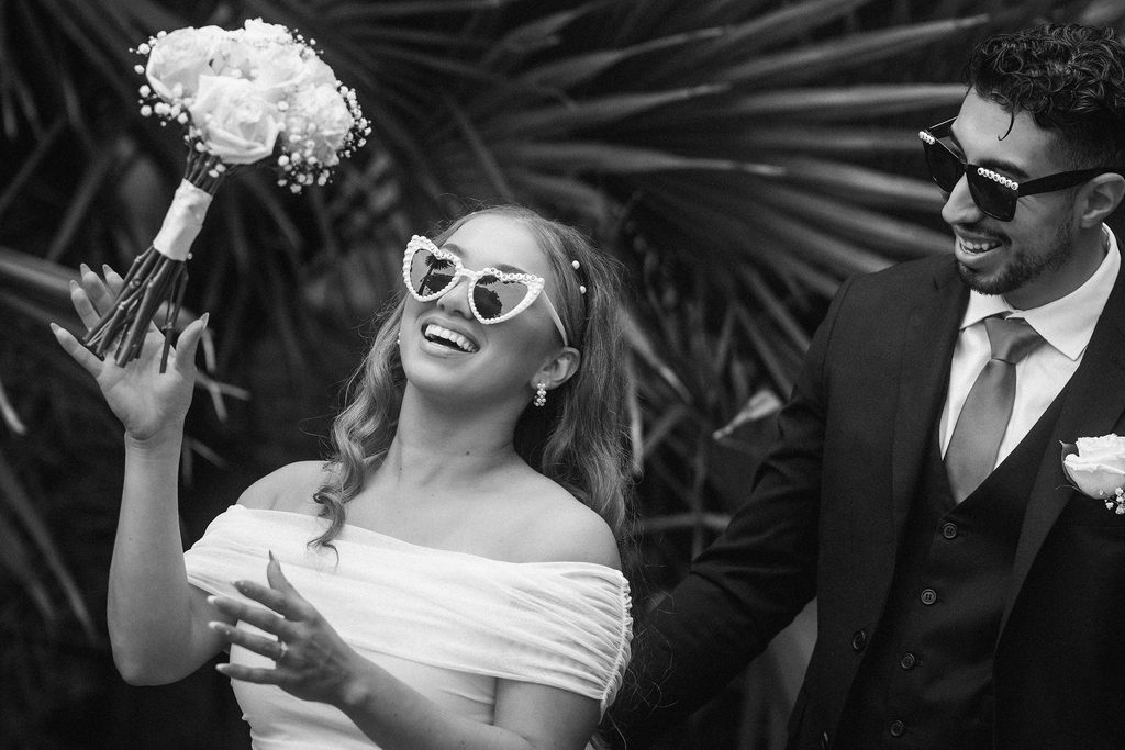 Black-and-white portrait of Vanessa laughing in heart-shaped sunglasses