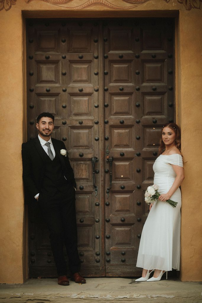 Vanessa and Bryant posed beside carved wooden courthouse doors