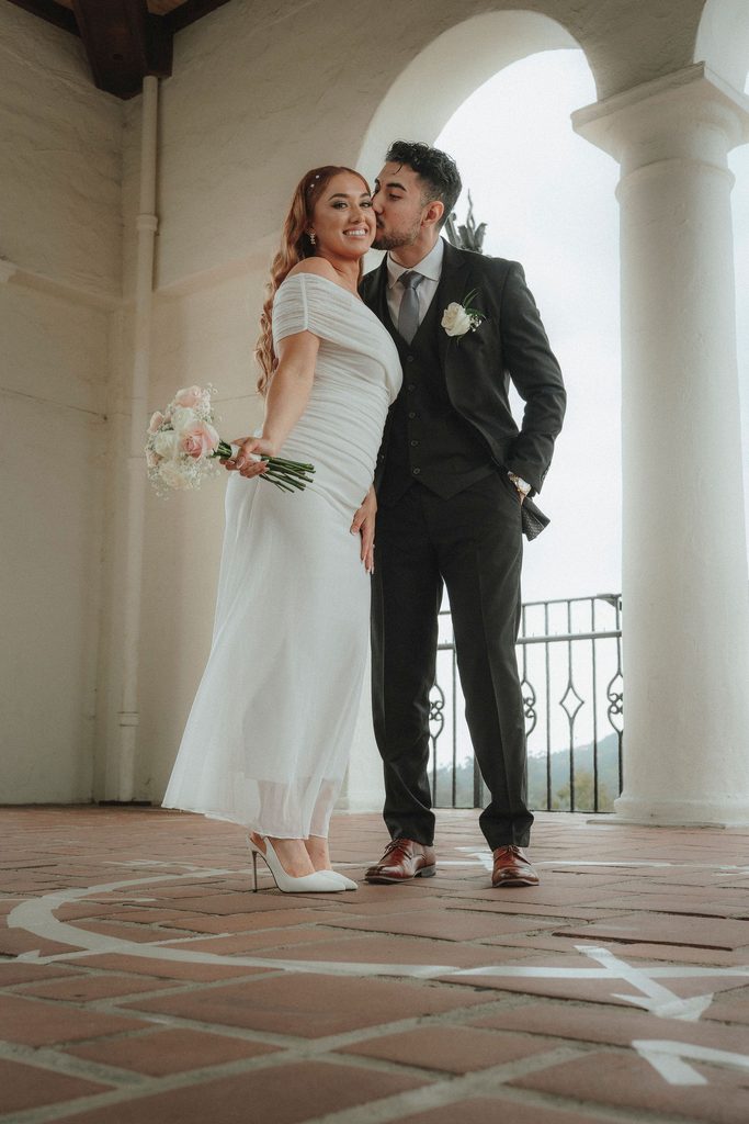 Vanessa and Bryant kissing beneath an arch at the Santa Barbara Courthouse