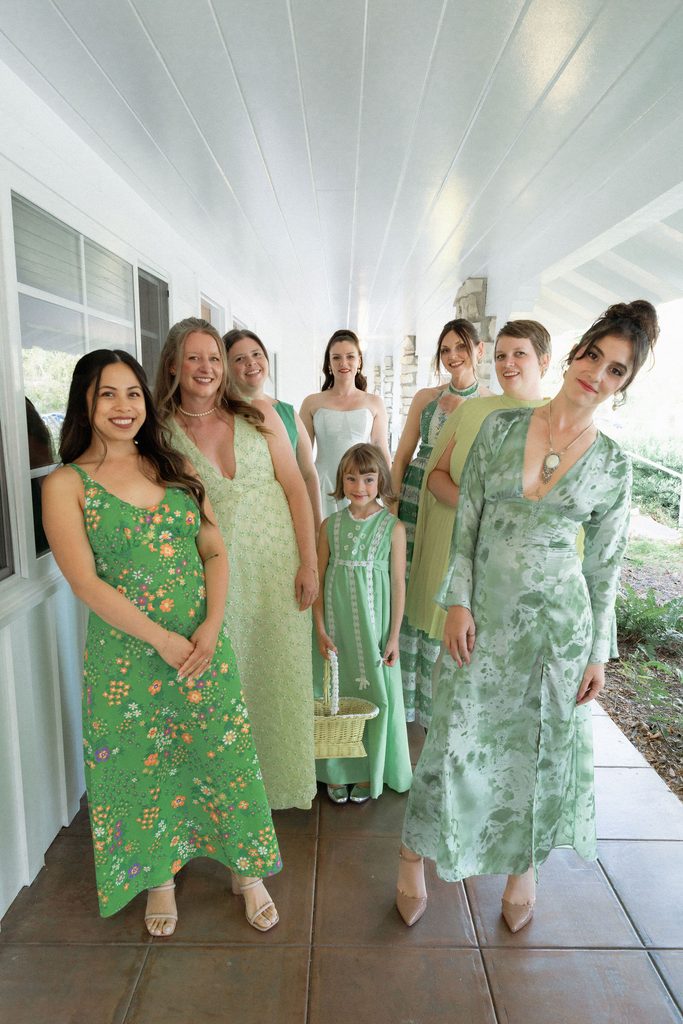 Catie with her wedding party in coordinated green dresses at the Madonna Inn