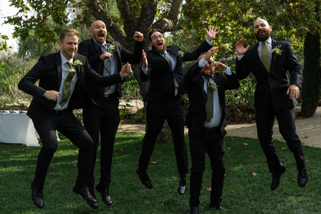 Groomsmen jumping together on the lawn at the Madonna Inn