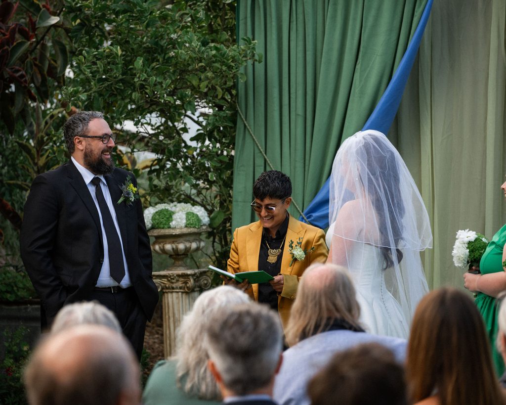 Catie and Tracy facing each other during their outdoor wedding ceremony